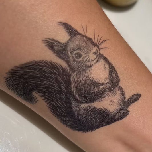 SteezyInk Squirrel Tattoo on arm, detailed black design, woodland charm.