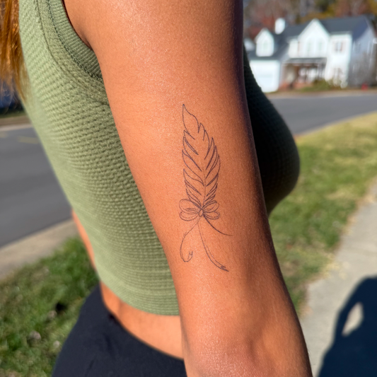Feather Touch temporary tattoo, elegant feather design on arm, plant-based Pure Black Ink™.