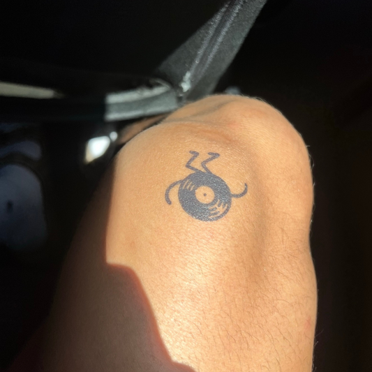 SteezyInk Groovy Vinyl temporary tattoo on knee, black record design