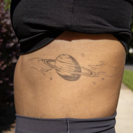 SteezyInk Cradle Saturn temporary tattoo on skin, black and white design. Body art for self-expression.