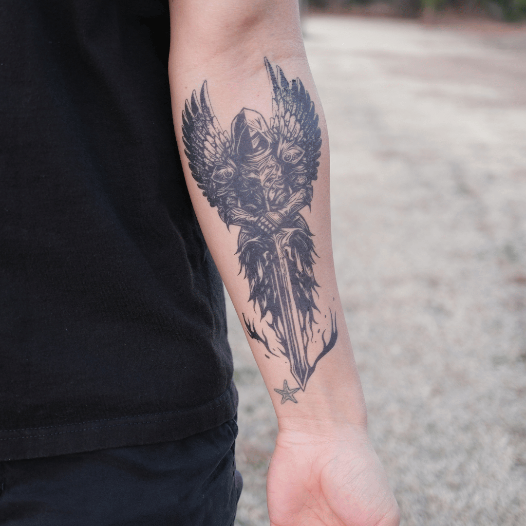 SteezyInk Angel of Valor temporary tattoo applied on forearm, black ink design of warrior with large wings and sword.