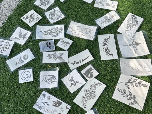 Temporary tattoo stickers with various designs scattered on artificial turf.